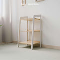 The image showcases an empty small Montessori-style toy storage shelf with a white and natural wood finish. The shelf features three tiers, offering ample space for organizing children's toys and items. The frame is painted white, while the shelves retain their natural wood look, creating a clean and modern aesthetic. Positioned against a light-colored wall in a softly lit room, the minimalist design enhances the bright and organized atmosphere, making it an ideal addition to a child's play area or bedroom.