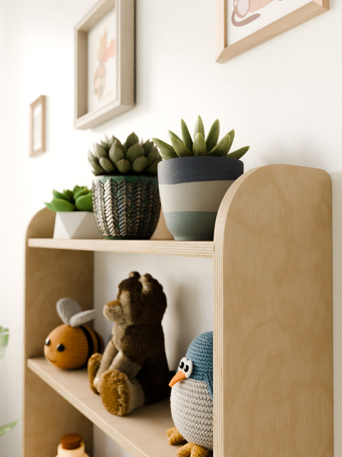 Detailed side view of a Montessori wall-mounted shelf, highlighting wooden craftsmanship and decorative items like plants and toys.