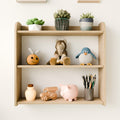 Front close-up of a Montessori wall-mounted shelf, neatly organized with toys, plants, and art supplies, perfect for a modern nursery.